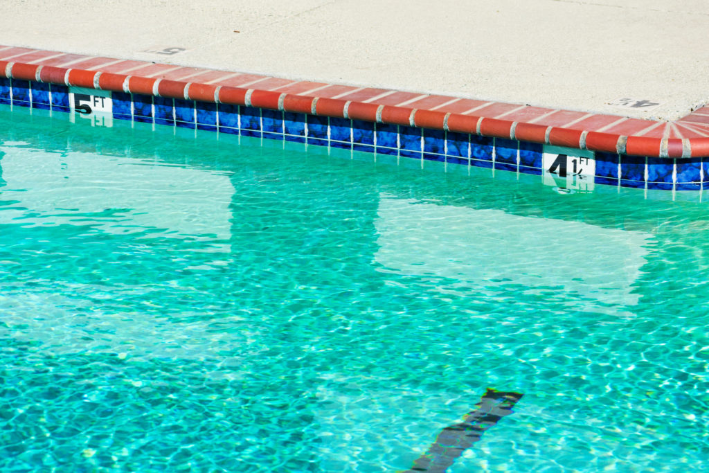 A commercial swimming pool has blue water and depth markers at four and a half feet and pool accessories.